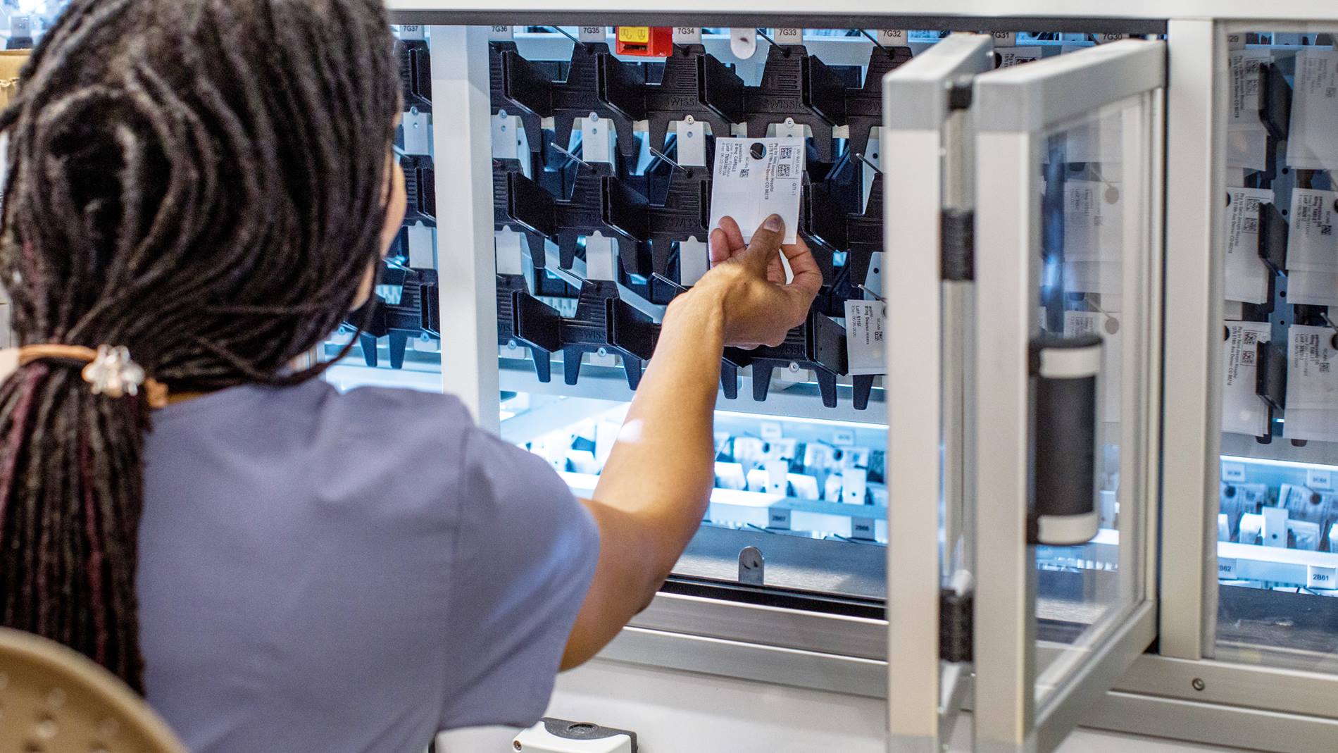 Pharmacy technician using PillPick automated medication packaging and dispensing system